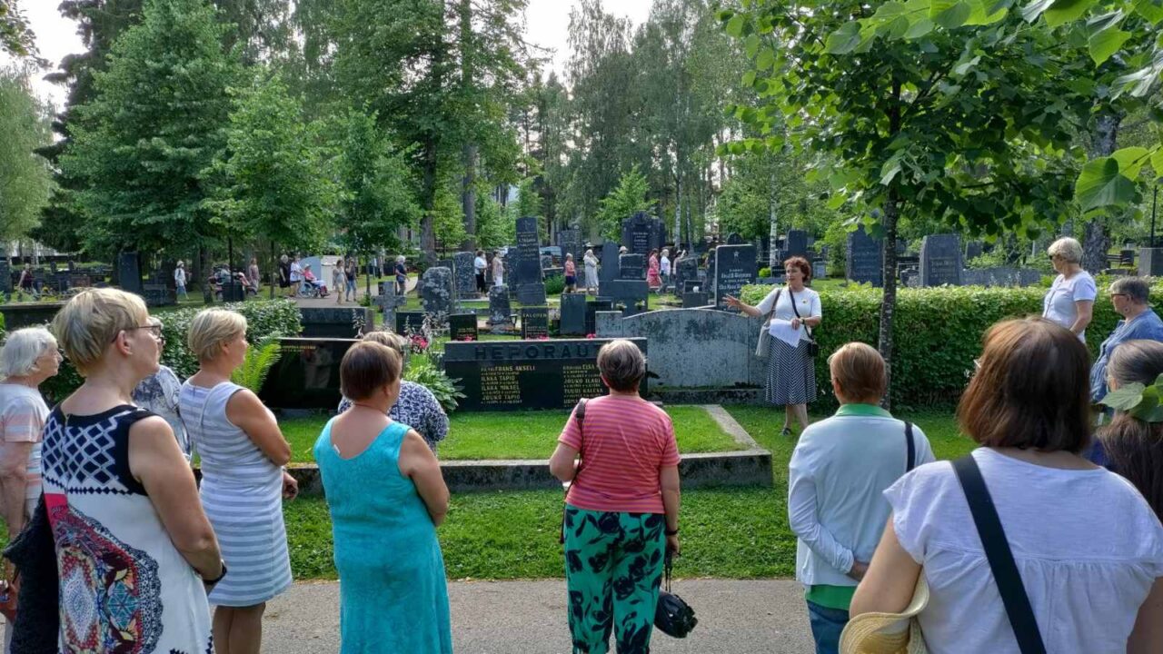 Opas kertomassa tarinaa hautausmaalla. Etualalla kuuntelijoita.