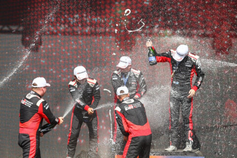 Rally drivers cheering on the podium.