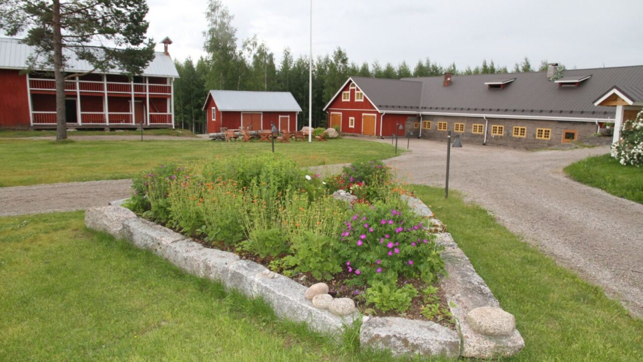 Piha-alueen rakennuksia ja kukkapenkki.